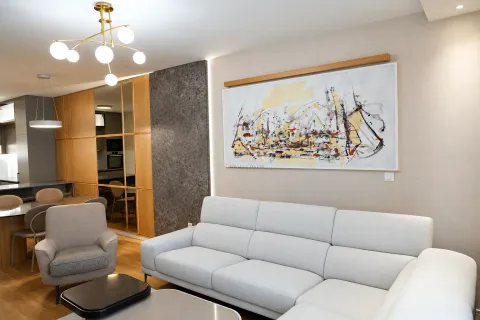 Living room with a comfortable sofa, armchair, coffee table, and a large piece of art on the wall. - image 5
