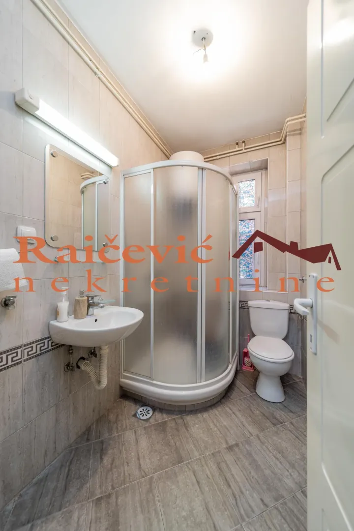 Small bathroom with a shower cabin, washbasin, and toilet.