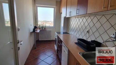 Manja kuhinja sa drvenim elementima i prozorom na kraju prostorije. - image 2