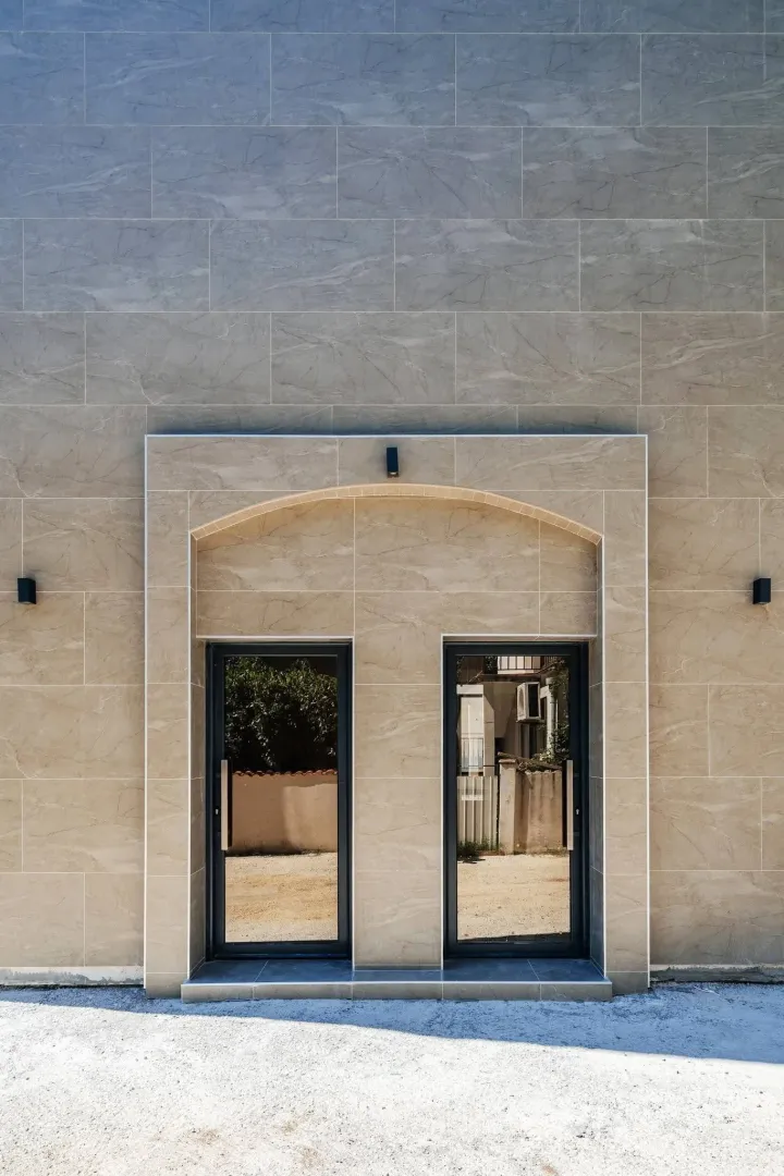 Modern stone building facade with double glass entrance doors.