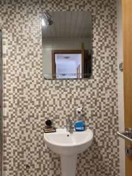 Small bathroom with a sink and mirror on a mosaic-tiled wall. - image 9