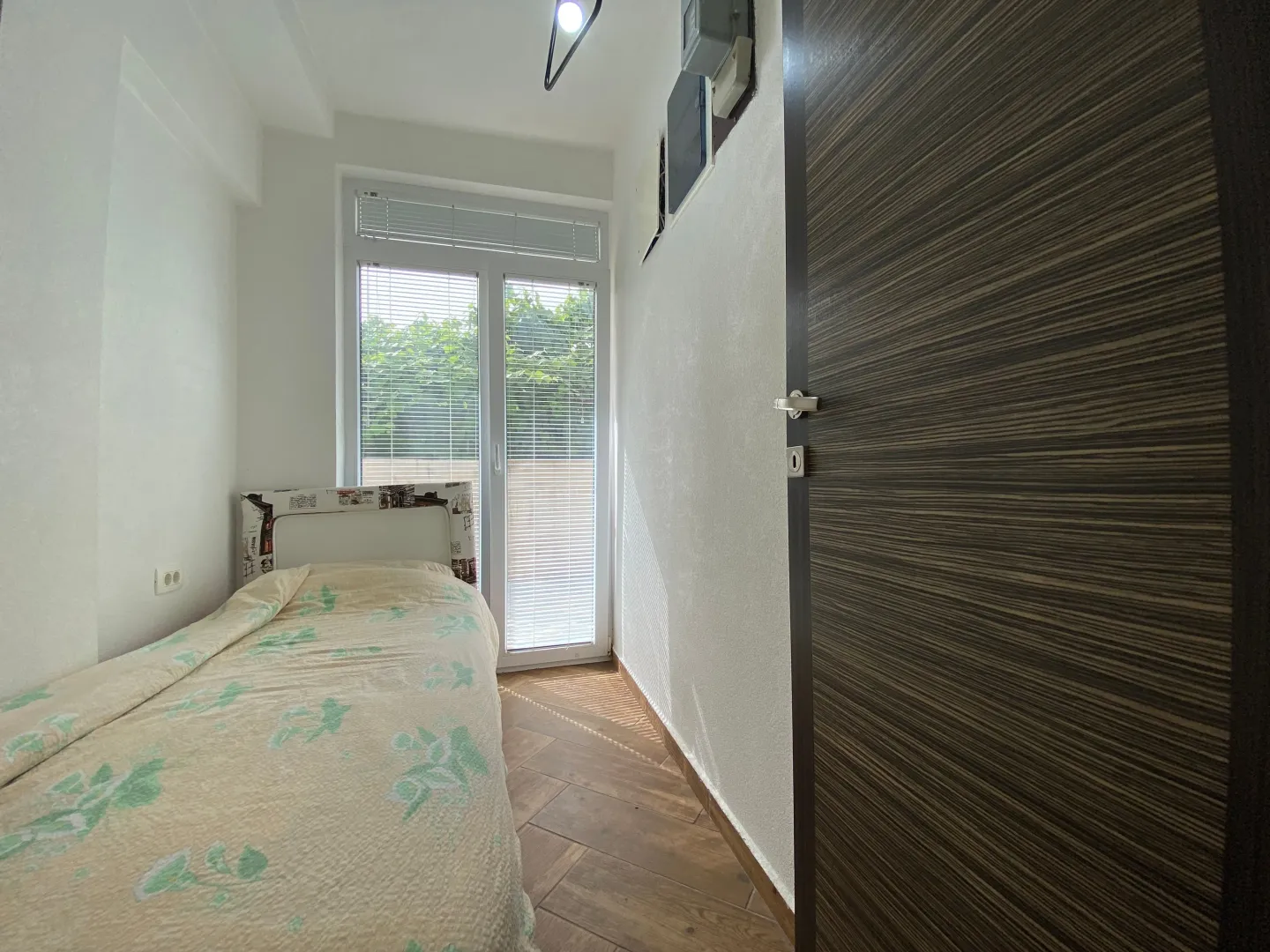 Small bedroom with a bed and balcony doors.