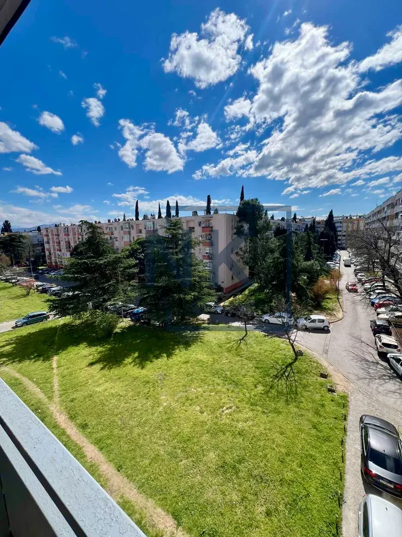 View from the terrace overlooking surrounding buildings, greenery, and parking.
