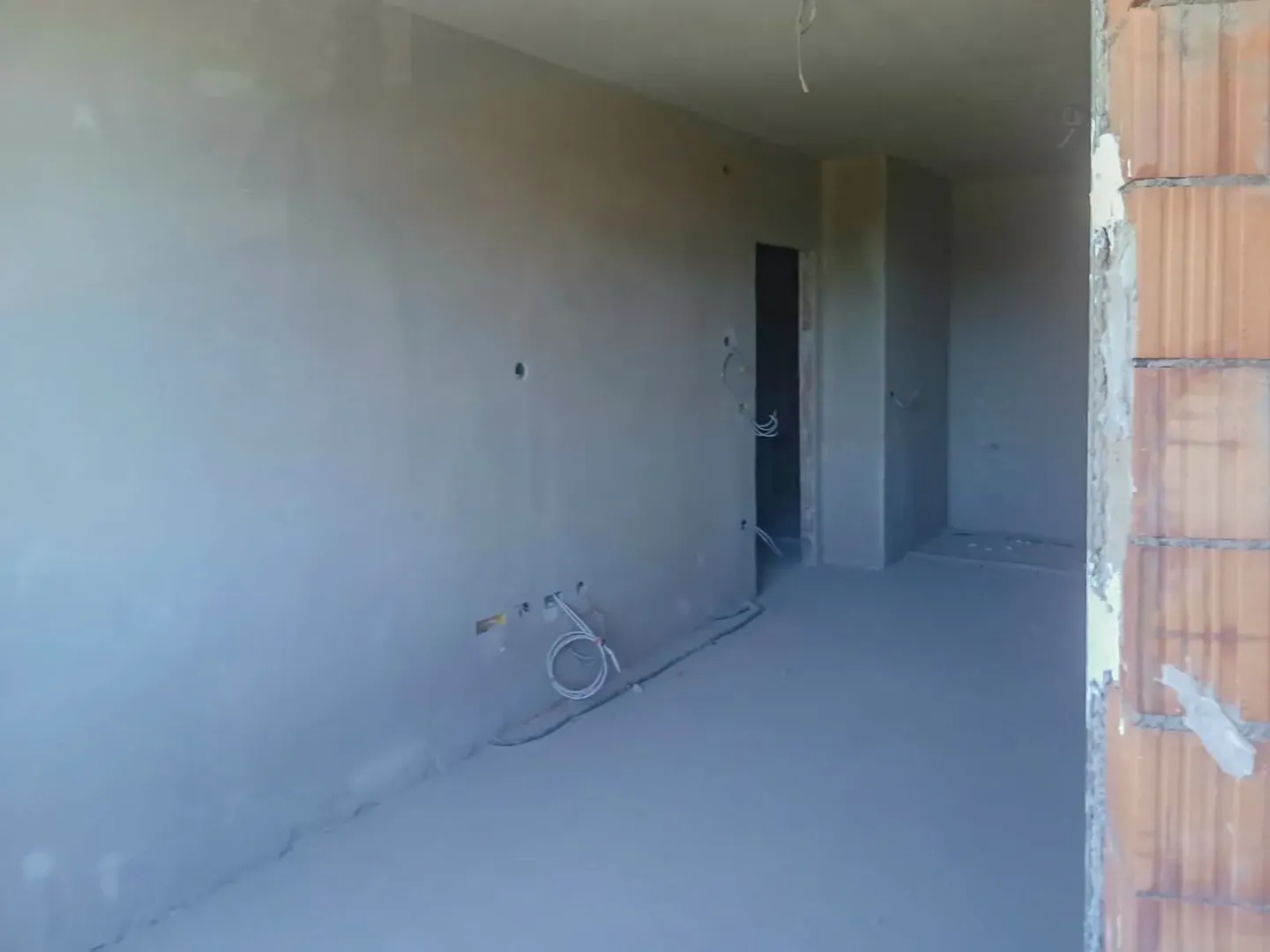 Pogled na nenamještenu prostoriju u fazi grubih radova sa ožbukanim zidovima.