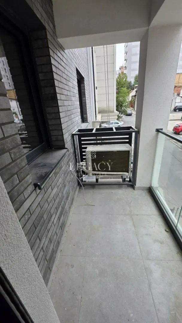 Pogled na prostrani balkon sa spoljnom jedinicom klima uređaja.