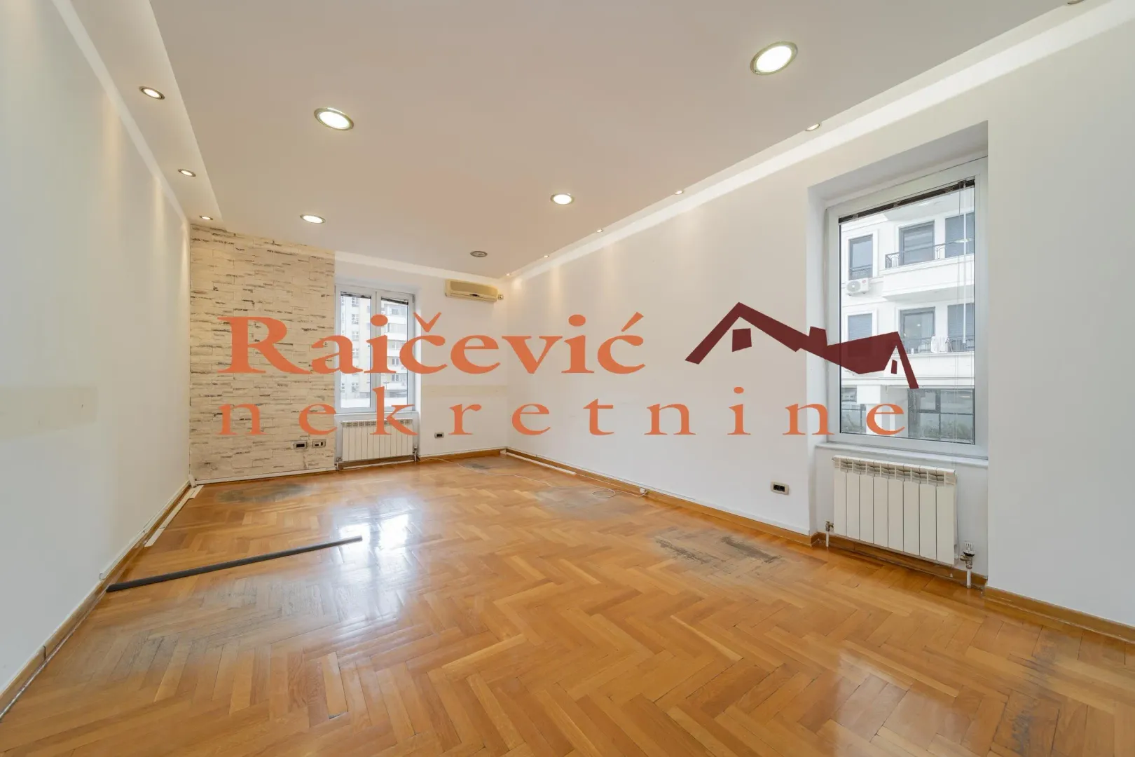 Empty room with parquet flooring and windows.