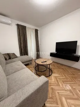 Dnevna soba sa garniturom, stočićem, televizorom i parketom na podu. - image 3