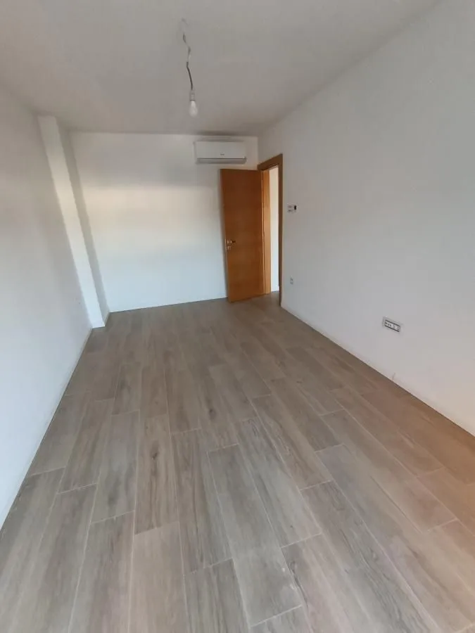 Empty room with white walls, wooden flooring and a door.