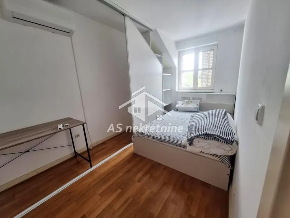 Small bedroom with a bed, desk, and built-in wardrobe.