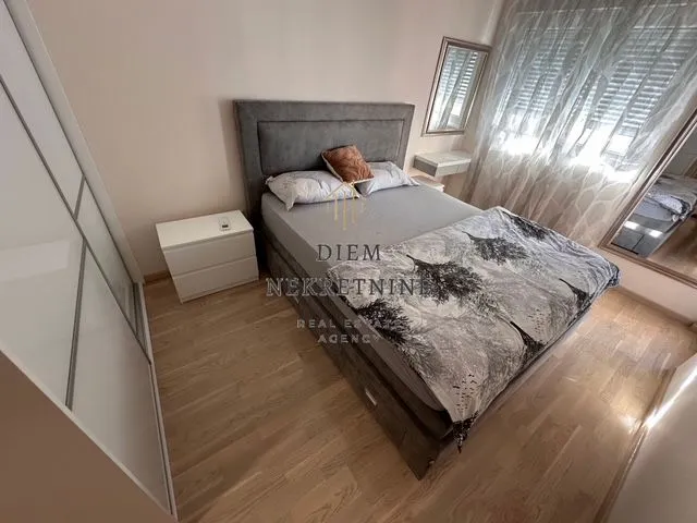 A furnished bedroom with a double bed, wardrobe, and window.