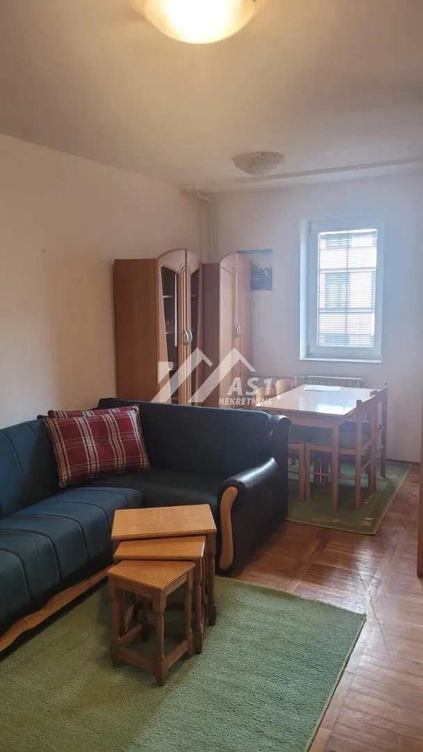 Dnevna soba sa garniturom, drvenim nameštajem i trpezarijskim stolom.