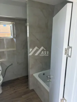 Tiled bathroom with a bathtub and a window. - image 7