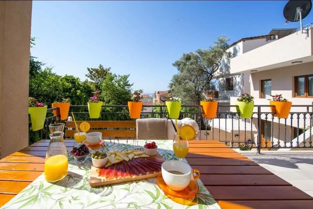 A table with food and drinks on a sunny terrace with a view of the surroundings.