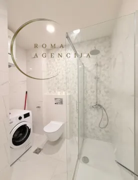 Modernly equipped bathroom with a walk-in shower and washing machine. - image 13