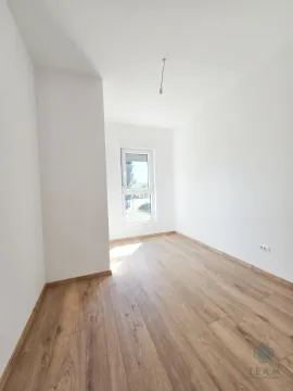 Prazna soba sa bijelim zidovima, drvenim podom i prozorom. - image 4