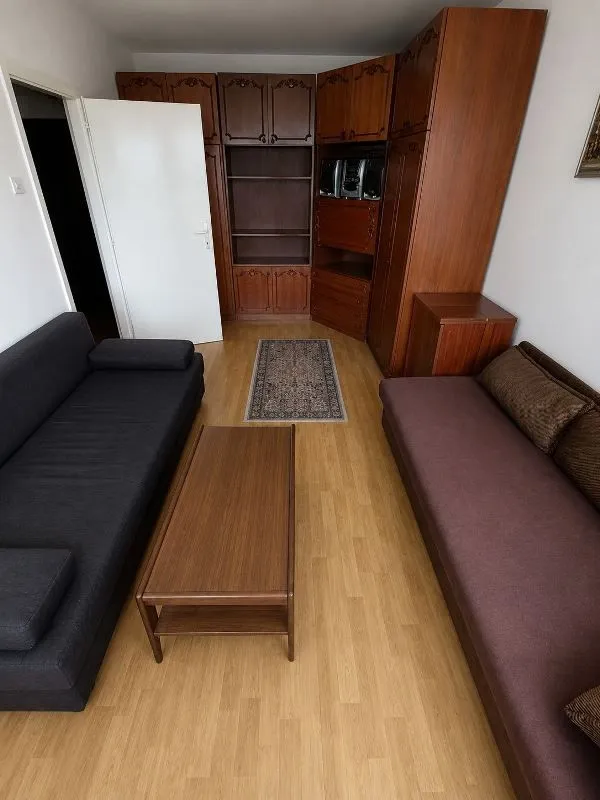 Dnevna soba sa garniturom za sedenje, drvenim ormarima i stočićem.