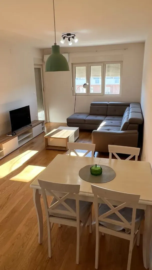 Dnevni boravak sa garniturom, TV-om i trpezarijskim stolom.