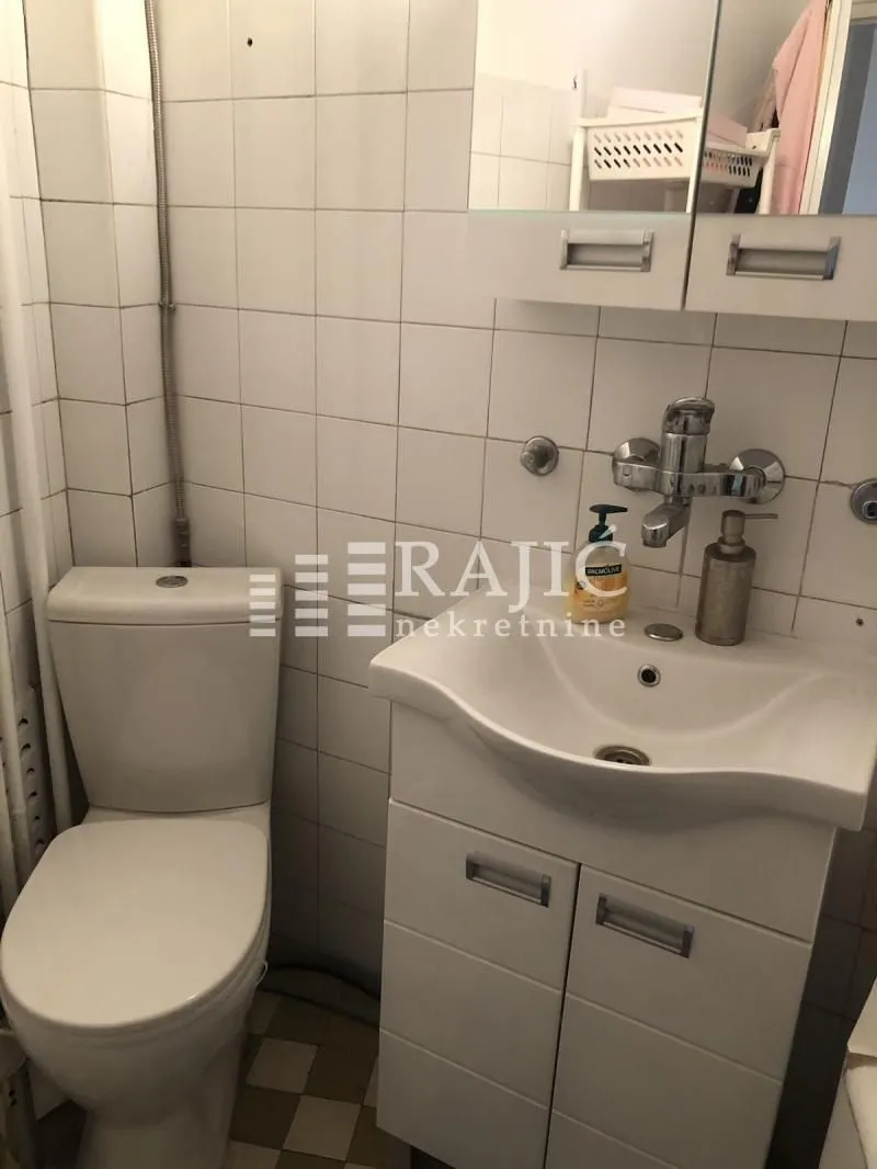 Smaller bathroom with a toilet, washbasin, and cabinet.