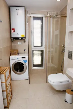 Savremeno opremljeno kupatilo sa tuš kabinom, wc šoljom i veš mašinom. - image 4
