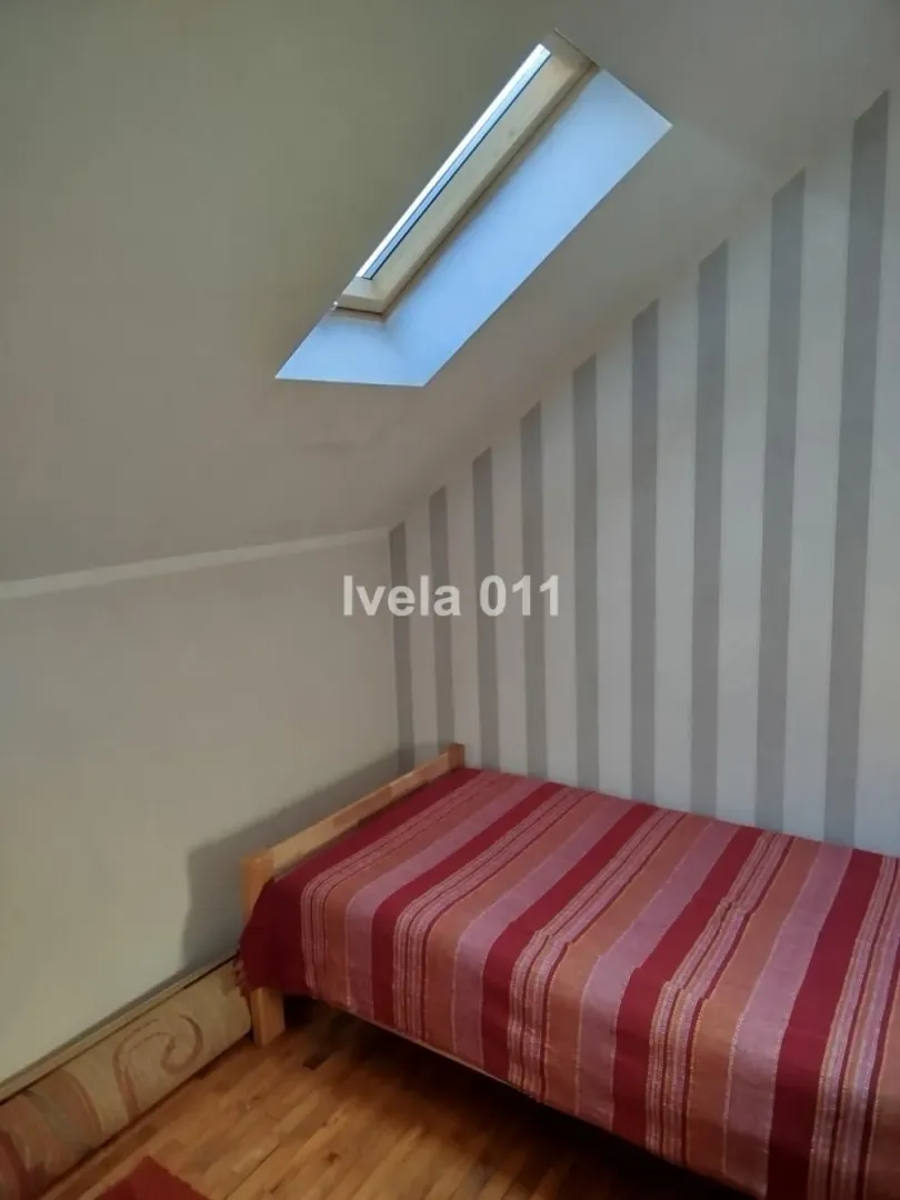 Manja spavaća soba pod kosinom sa krevetom i krovnim prozorom.