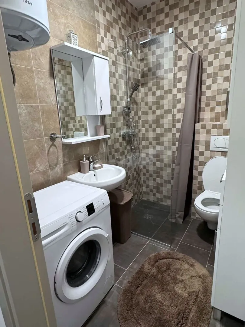 Bathroom equipped with a shower cabin, washbasin, toilet, and washing machine.