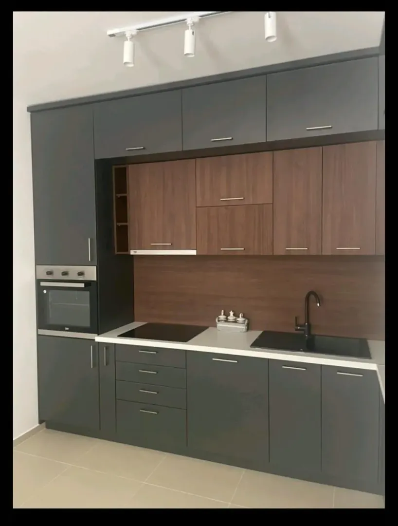 Moderna kuhinja sa tamnim elementima i ugrađenim uređajima.
