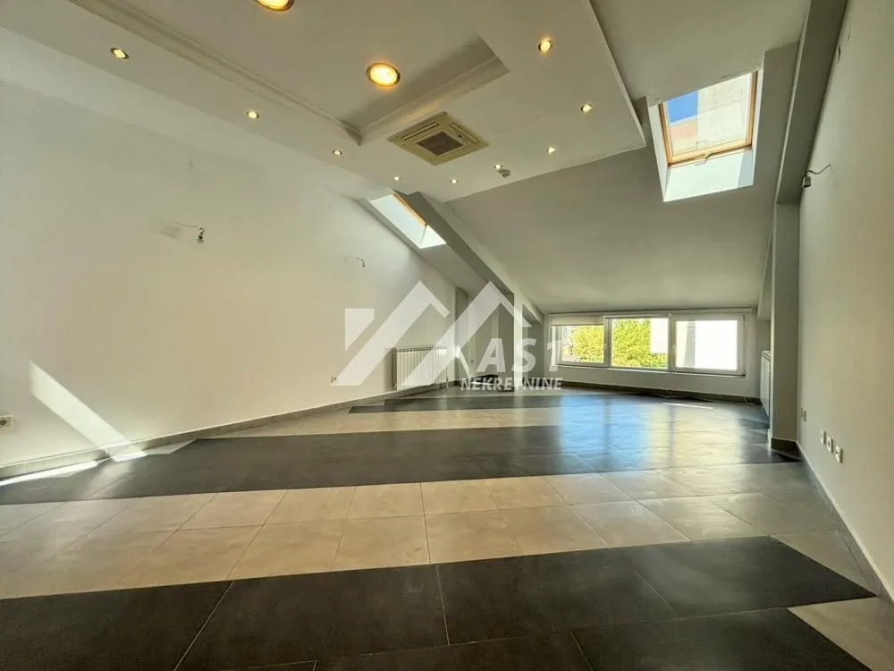 Spacious empty room with dropped ceiling, lighting, and tiled floor in an attic.