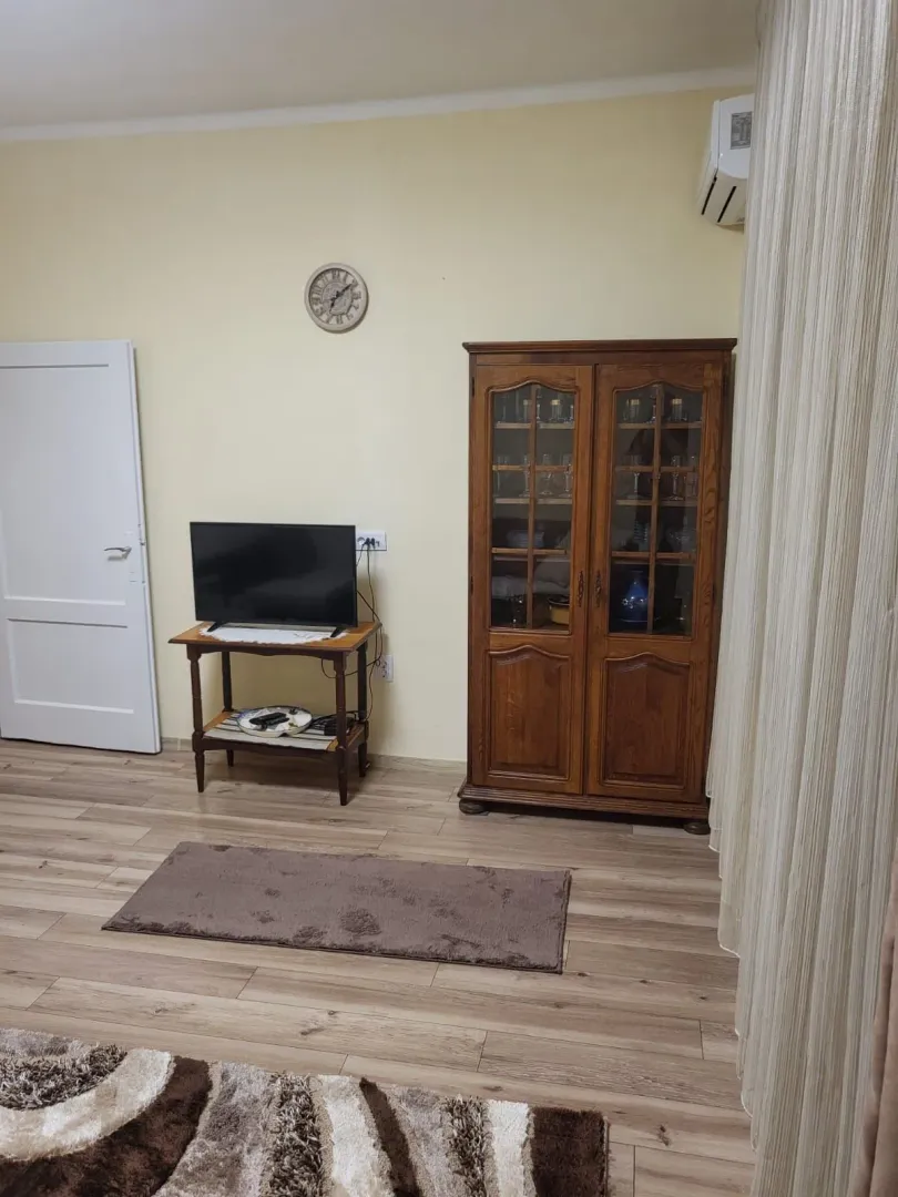 Dnevna soba sa drvenim ormarom, televizorom na komodi i laminatnim podom.