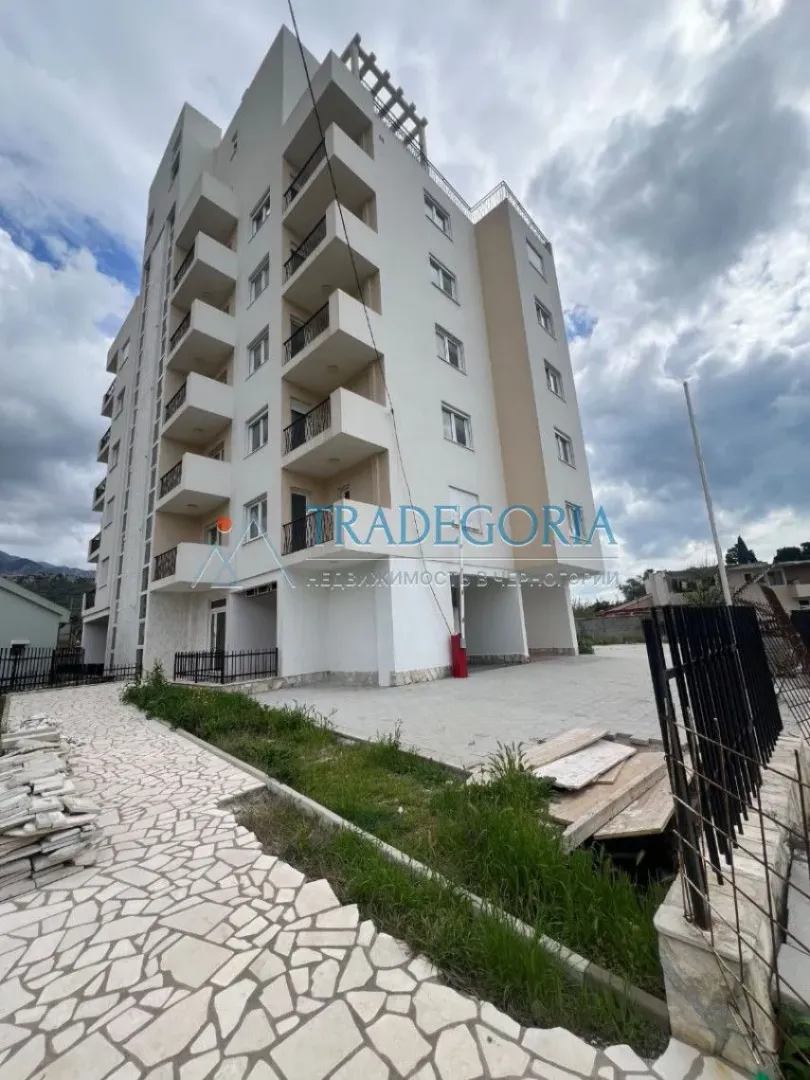 Pogled na spoljašnjost stambene zgrade sa terasama i popločanim dvorištem.