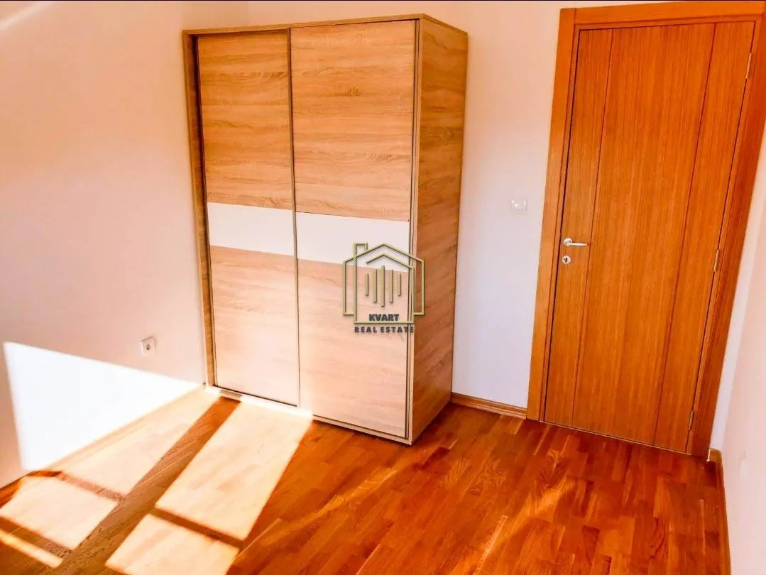 Spavaća soba sa drvenim ormarom i drvenim podom.