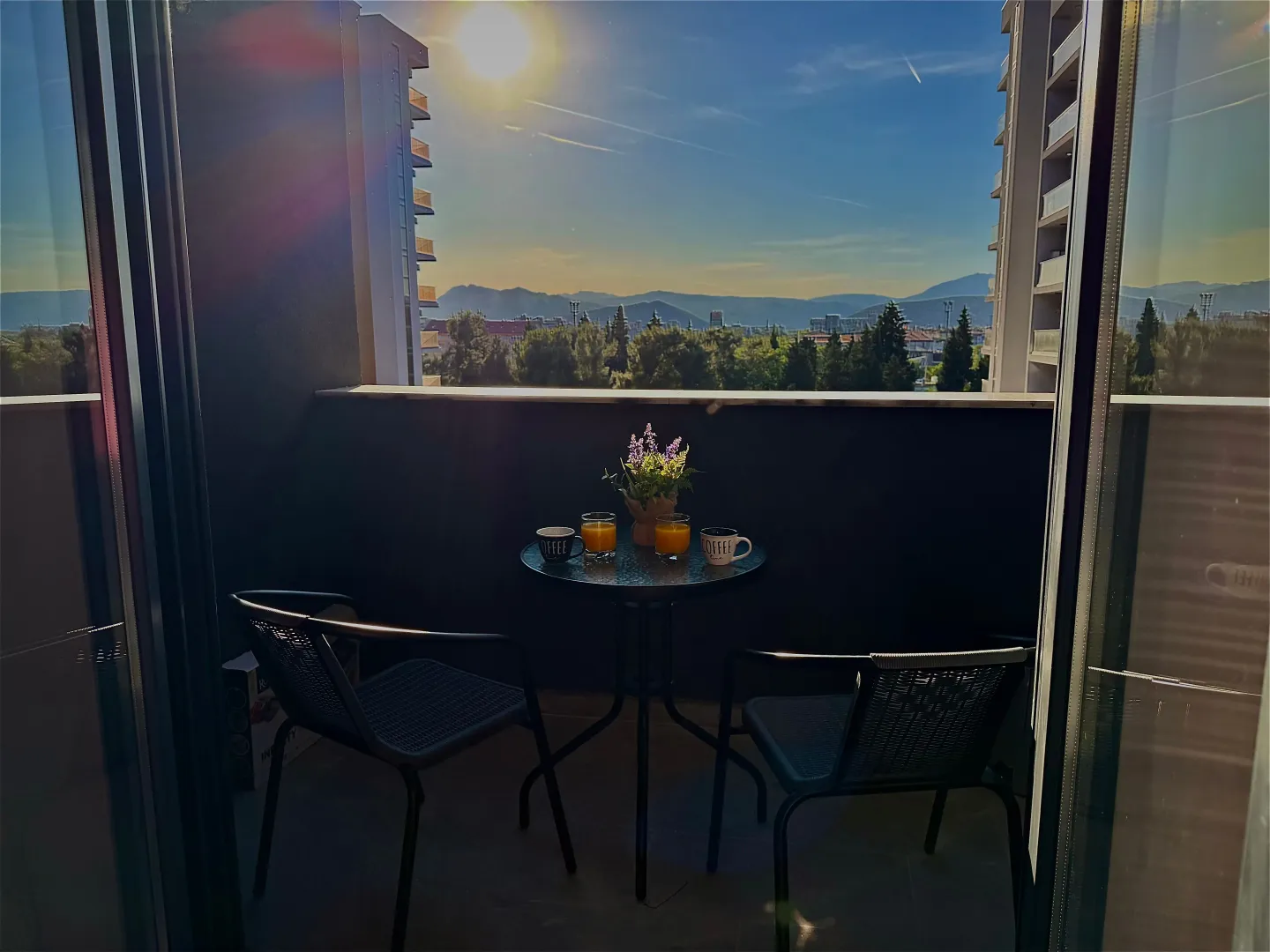 Namješten balkon sa stolom, stolicama i pogledom na grad i brda.