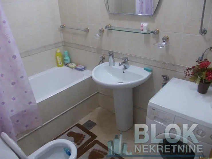 Smaller bathroom with a bathtub, washbasin, and washing machine.