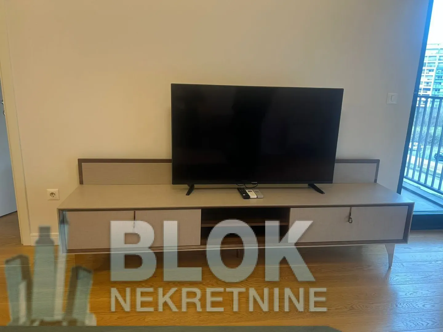 Living room with a TV on a media console and access to the terrace.