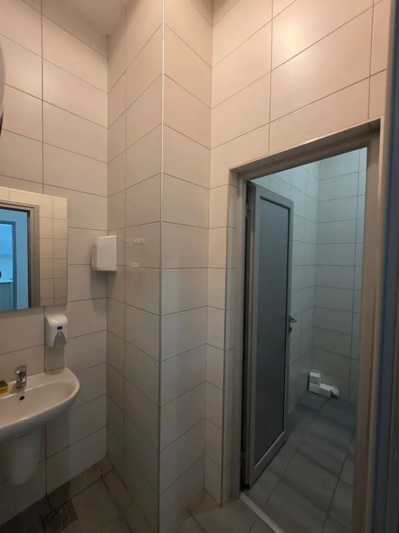 Tiled bathroom with a washbasin and a doorway leading to another room.