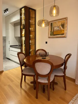 Dining area with a round wooden table and chairs, featuring an illuminated display cabinet and a view of the kitchen. - image 4