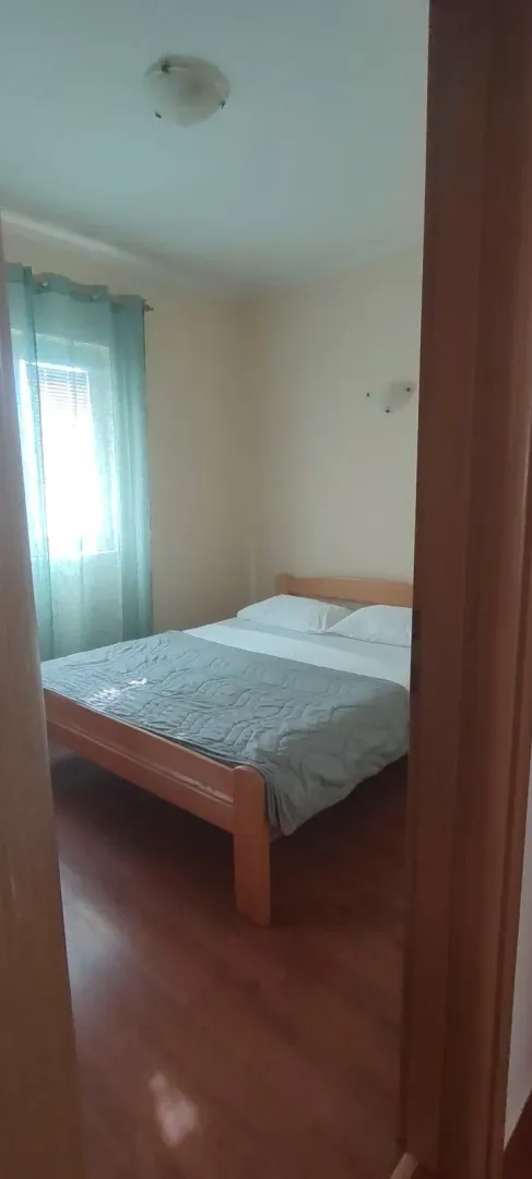 View of a bedroom with a wooden bed through an open door.