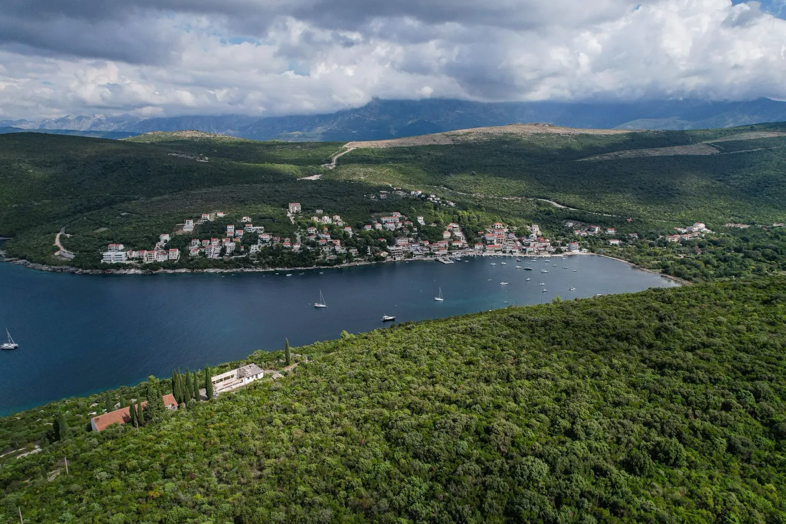 Pogled iz vazduha na zaliv, okolna brda i naselje.
