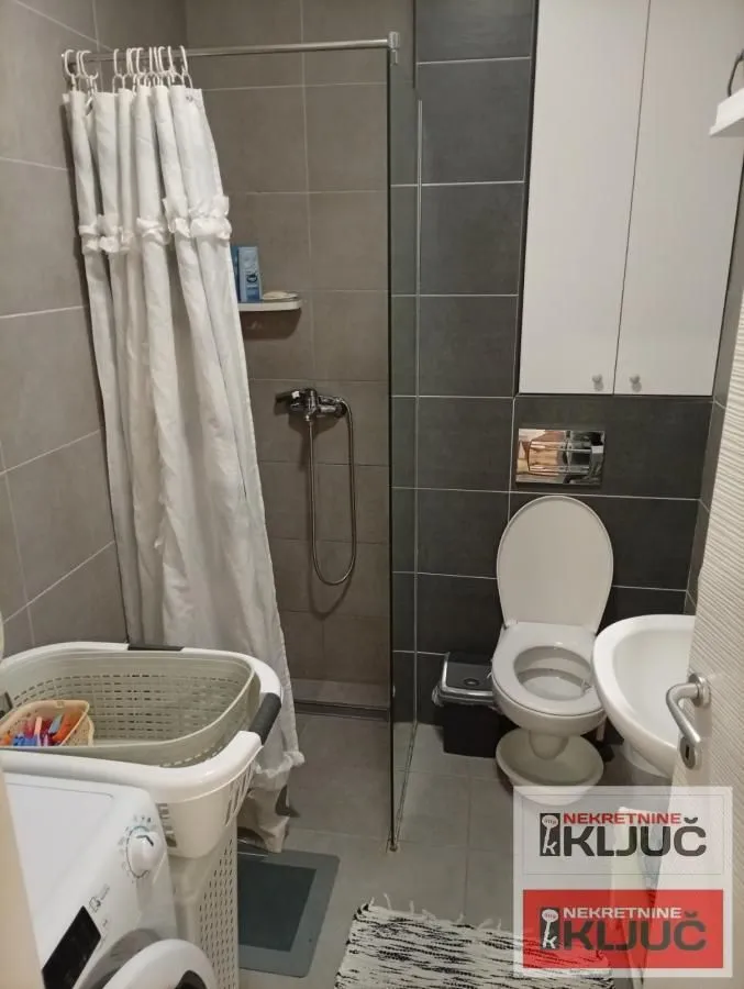 Kupatilo opremljeno tuš kabinom, toaletom i veš mašinom.