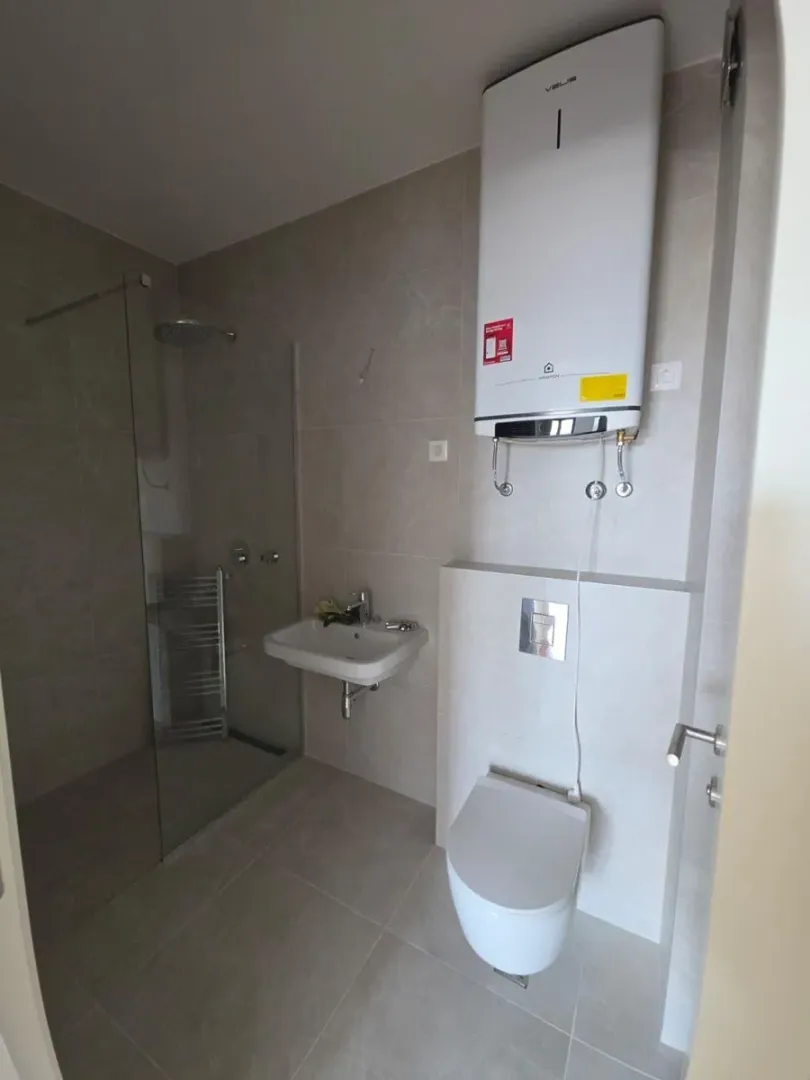 Moderno kupatilo sa tuš kabinom, umivaonikom, WC šoljom i bojlerom.
