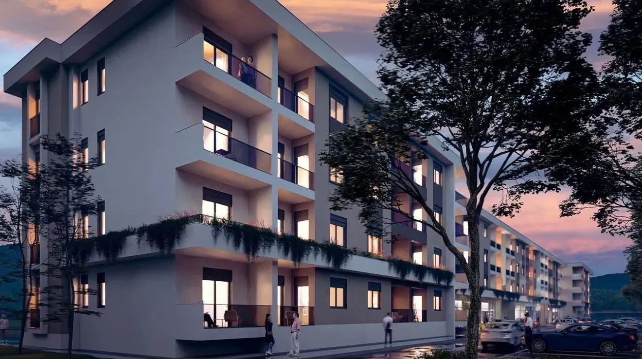 Pogled na spoljašnjost moderne stambene zgrade u sumrak.