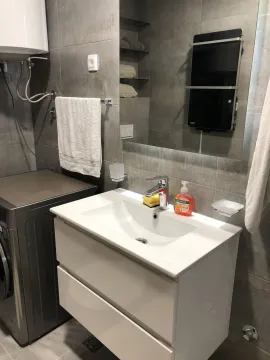 Modern bathroom with a white sink vanity, mirror, and grey tiles. - image 23
