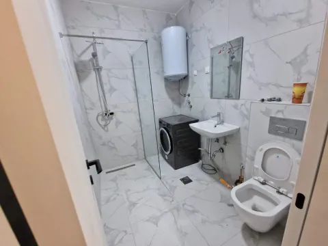 Moderne kupatilo obloženo keramičkim pločicama sa tuš kabinom, umivaonikom, WC šoljom i veš mašinom. - image 7