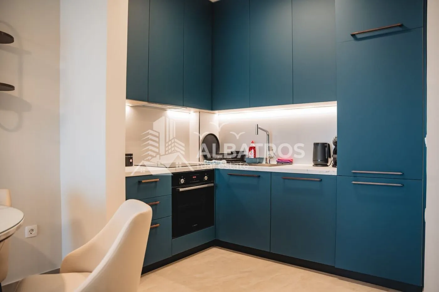 Modern blue kitchen with built-in appliances and lighting.