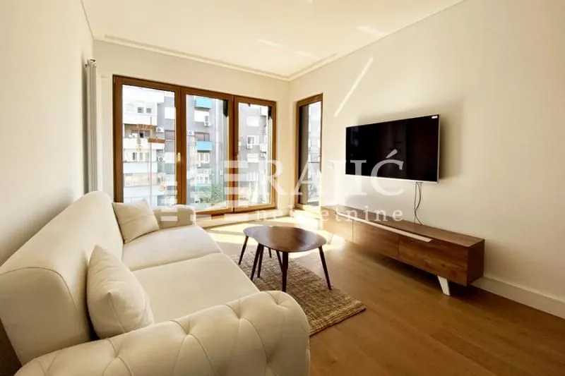 Living room with a sofa, TV, and large windows.