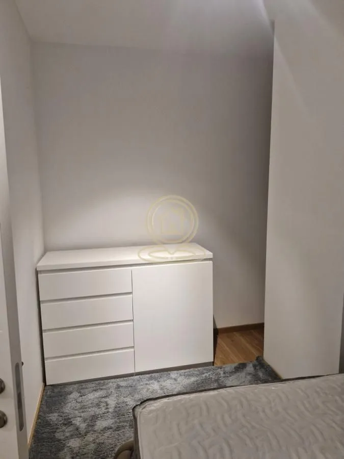 Manja spavaća soba sa belom komodom i krevetom.