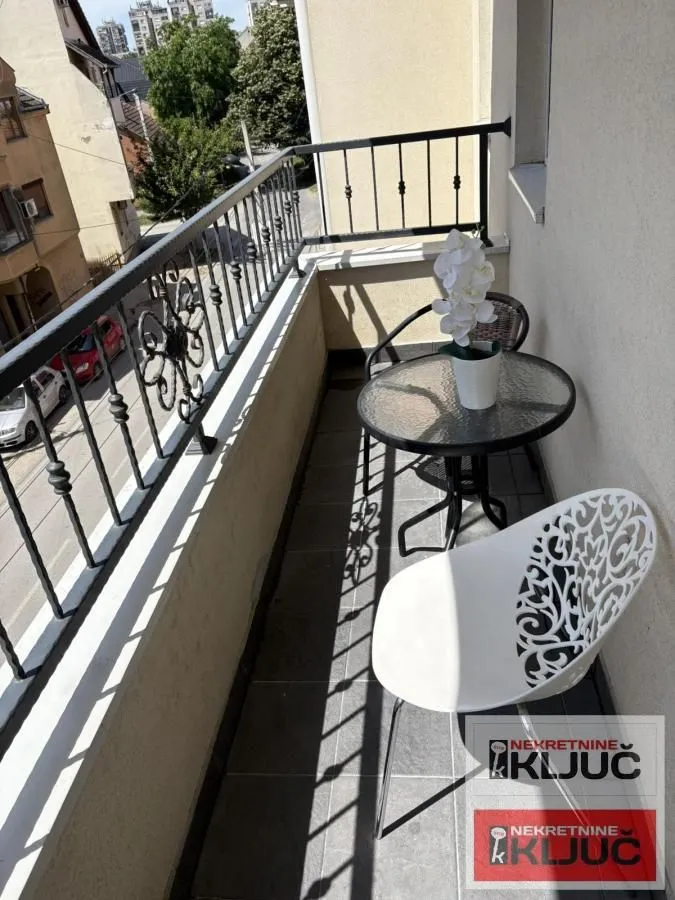 Manji namešteni balkon sa stolom i stolicama.