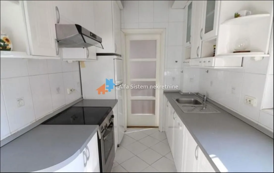 Small bright kitchen with white cabinets and grey countertops.