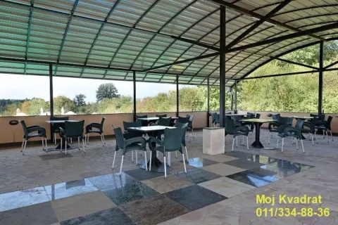Large covered terrace with tables and chairs and a view of greenery. - image 6