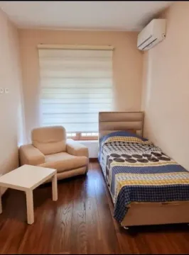 Smaller bedroom with a bed, an armchair, and an air conditioner. - image 3