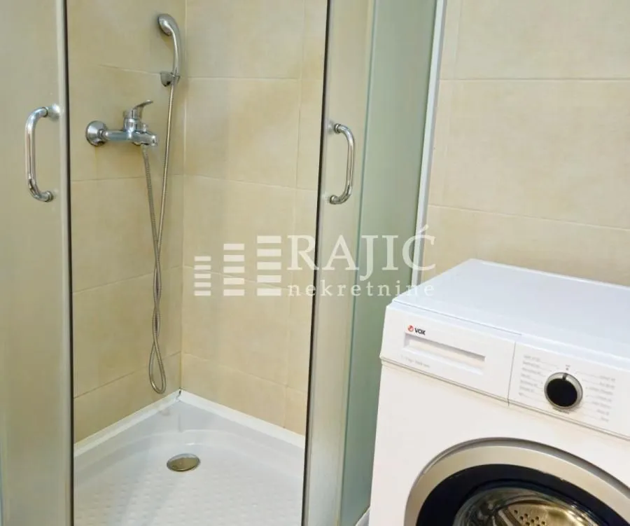 Small bathroom with a shower cabin and a washing machine.
